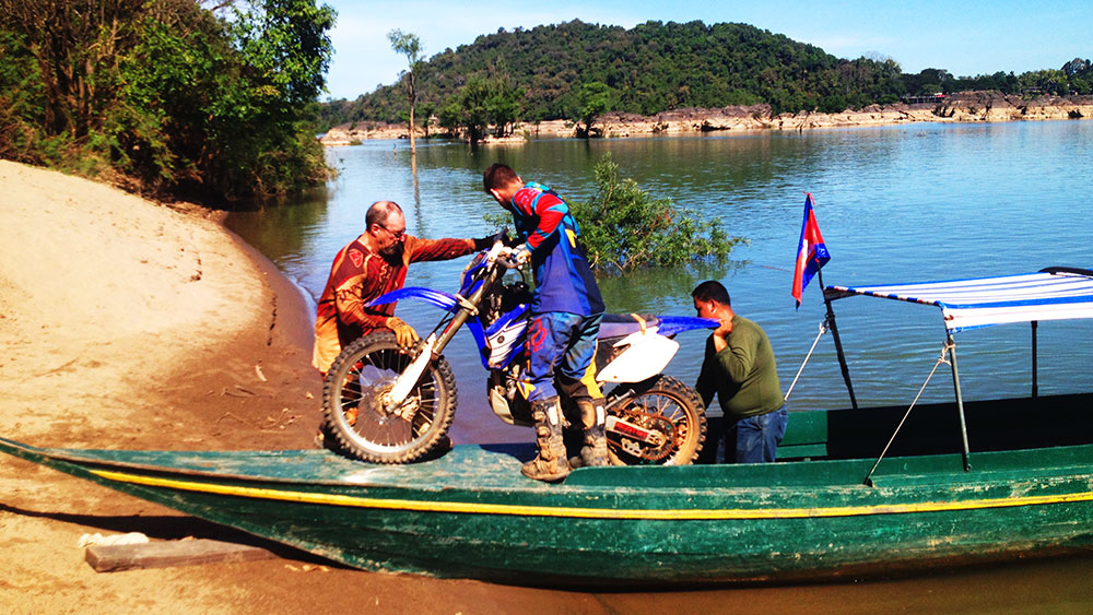 Loading a dirtbike onto a boat to cross the Mekong